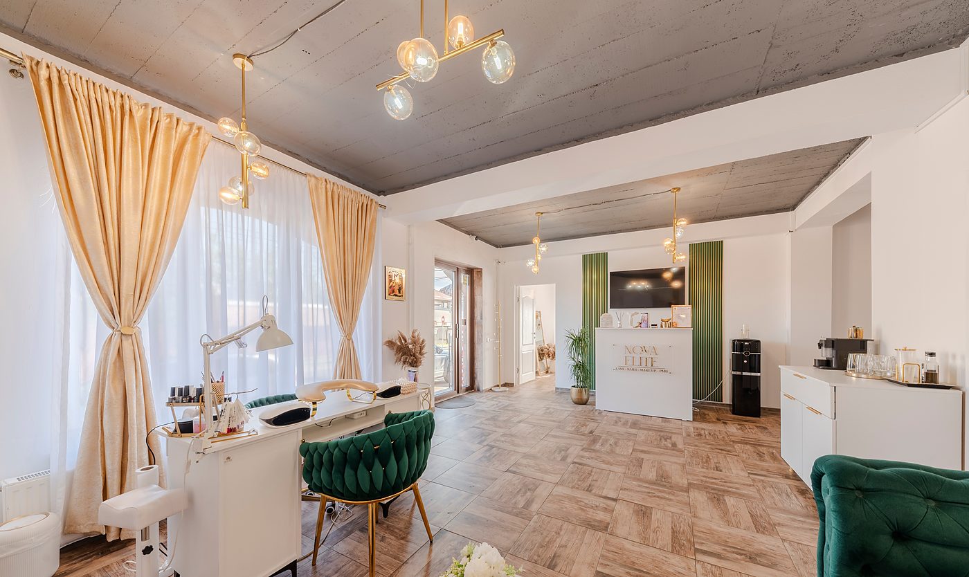 Salonul Nova Elite văzut în ansamblu: stația de manichiură lângă fereastră, recepția în fundal și pardoseala în model spic.